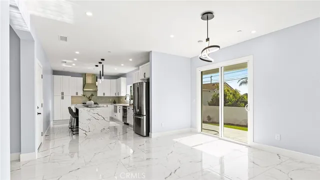 a view of a kitchen with kitchen island a refrigerator a sink and a chandelier