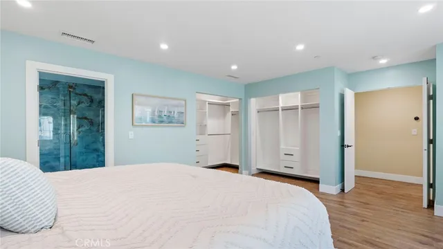 a bedroom with a large bed closet and wooden floor