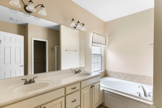 a bathroom with a tub sink double vanity and mirror