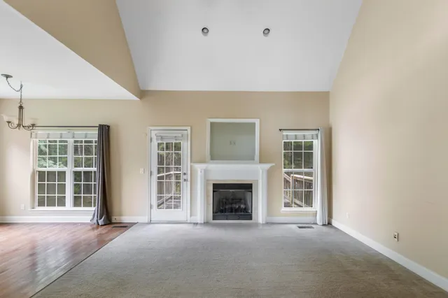an empty room with windows and fireplace