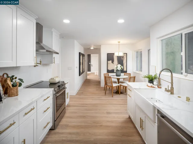 a kitchen with stainless steel appliances granite countertop a stove a refrigerator a sink a dining table and chairs with wooden floor