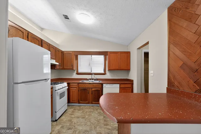 a kitchen with stainless steel appliances granite countertop a refrigerator a sink dishwasher a stove with wooden cabinets