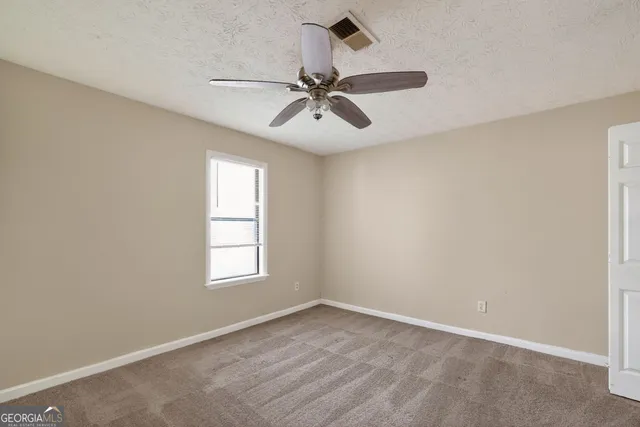 an empty room with windows and fan