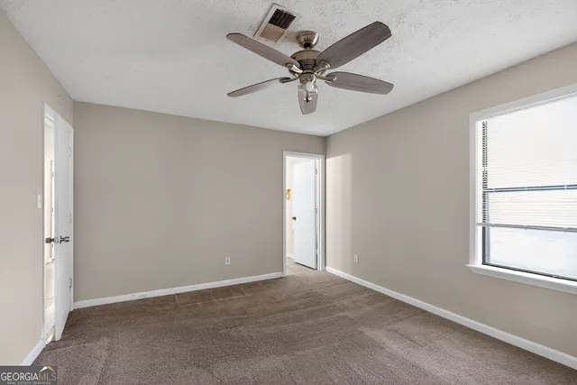an empty room with a window and a fan