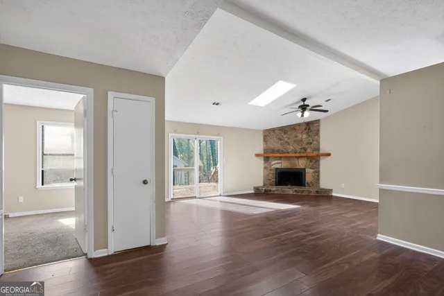 an empty room with wooden floor fireplace and windows