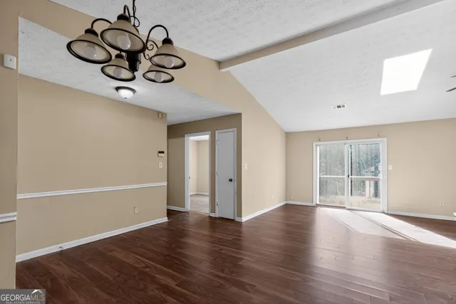 a view of an empty room with wooden floor and windows