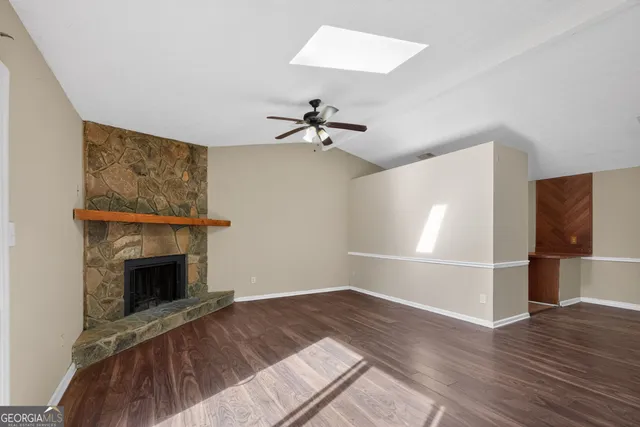 an empty room with fireplace wooden floor chandelier fan and windows