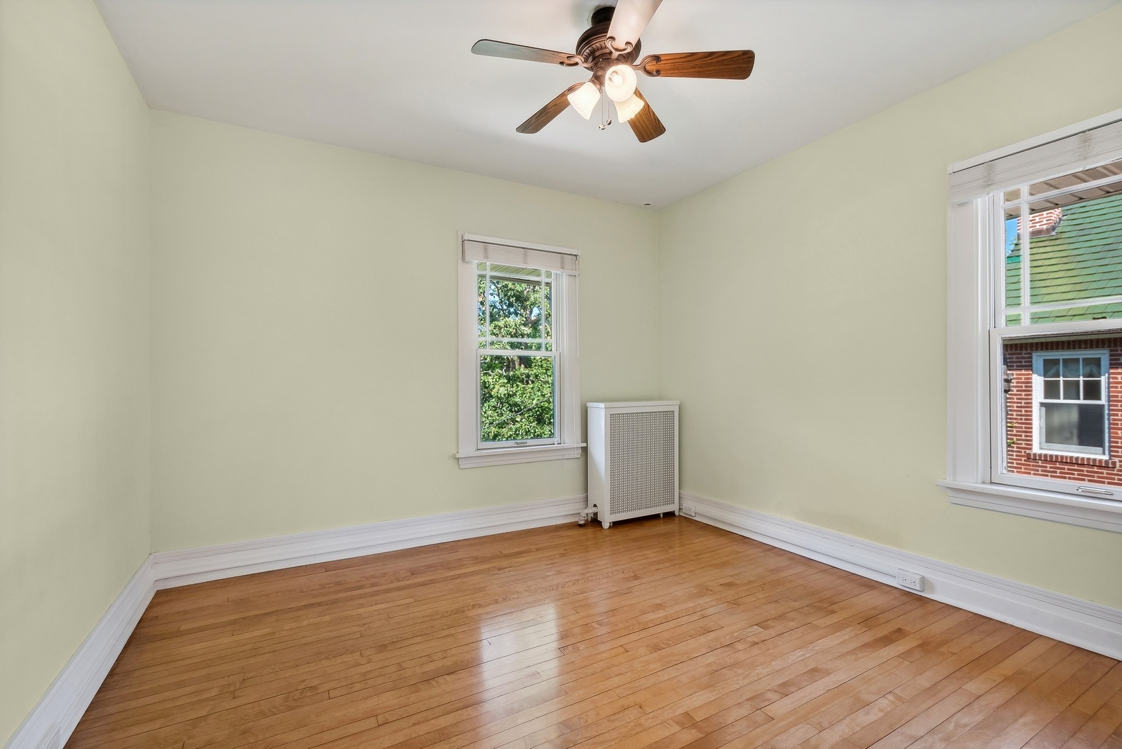 504 Maple Avenue Wilmette, IL 60091 - Photo 9 of 20 an empty room with wooden floor chandelier fan and windows