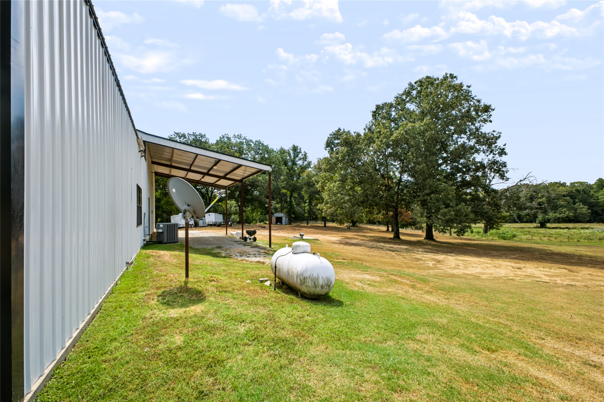 3607 South Half Bank Road Atoka, OK 74525 - Photo 51 of 82 Corrugated metal siding with a covered patio area, expansive grassy lawn, and mature trees