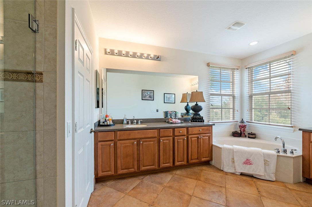4032 Cherrybrook Loop Fort Myers, FL 33966 - Photo 14 of 22 a spacious bathroom with a double vanity sink a mirror and a bathtub