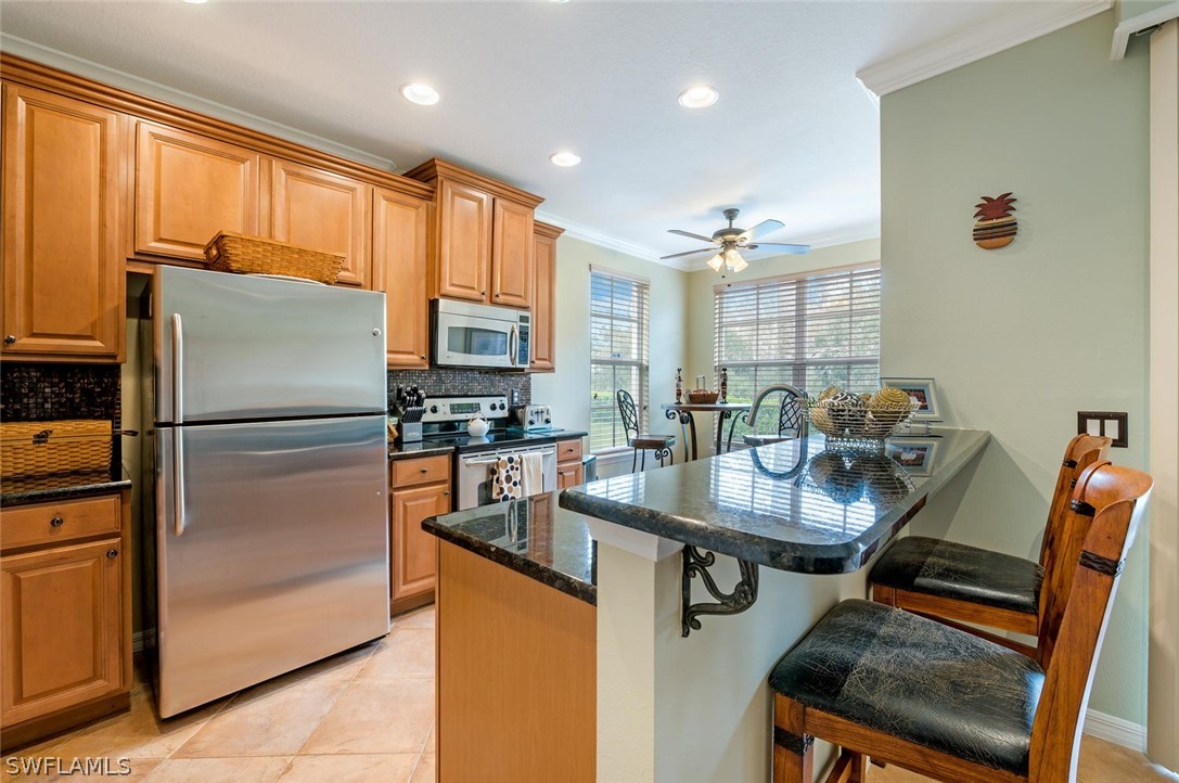 4032 Cherrybrook Loop Fort Myers, FL 33966 - Photo 7 of 22 a kitchen with stainless steel appliances granite countertop a refrigerator a sink dishwasher a stove and a dining table with wooden cabinet