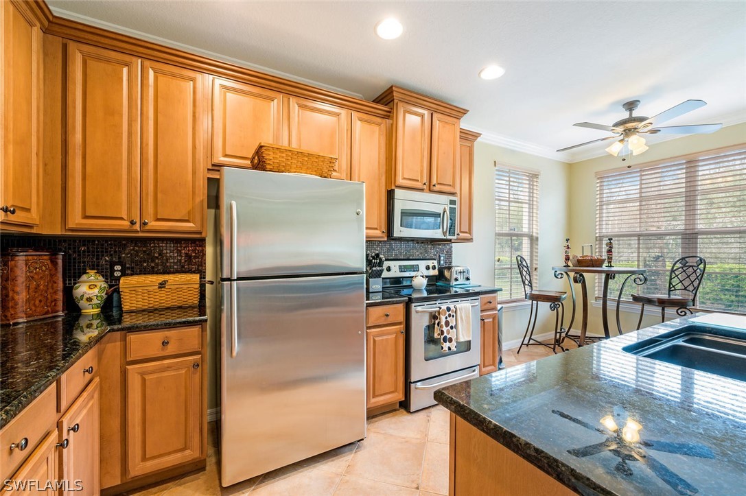 4032 Cherrybrook Loop Fort Myers, FL 33966 - Photo 8 of 22 a kitchen with stainless steel appliances granite countertop a refrigerator a stove a sink a dining table and chairs with wooden floor