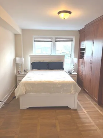 a large bed sitting in a bedroom next to a window and a lamp