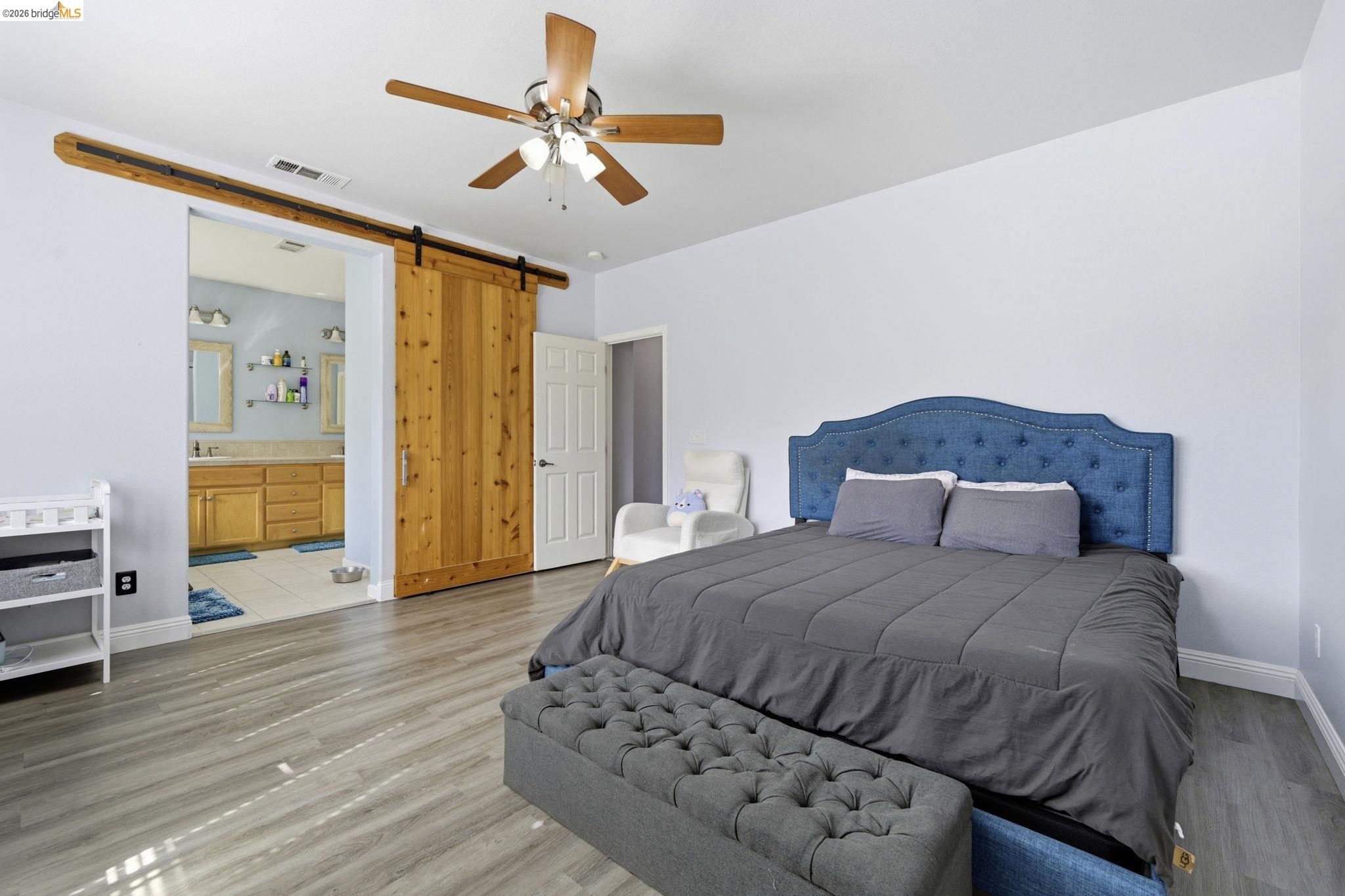 4568 Le Conte Circle Antioch, CA 94531 - Photo 21 of 36 Bedroom featuring light wood-style flooring, a barn door, ensuite bath, and a ceiling fan