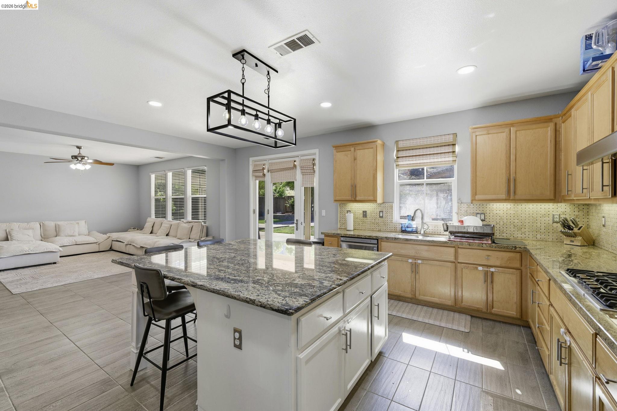 4568 Le Conte Circle Antioch, CA 94531 - Photo 36 of 36 Two tone kitchen with dark stone countertops, a kitchen breakfast bar, two tone color scheme, backsplash, and open floor plan