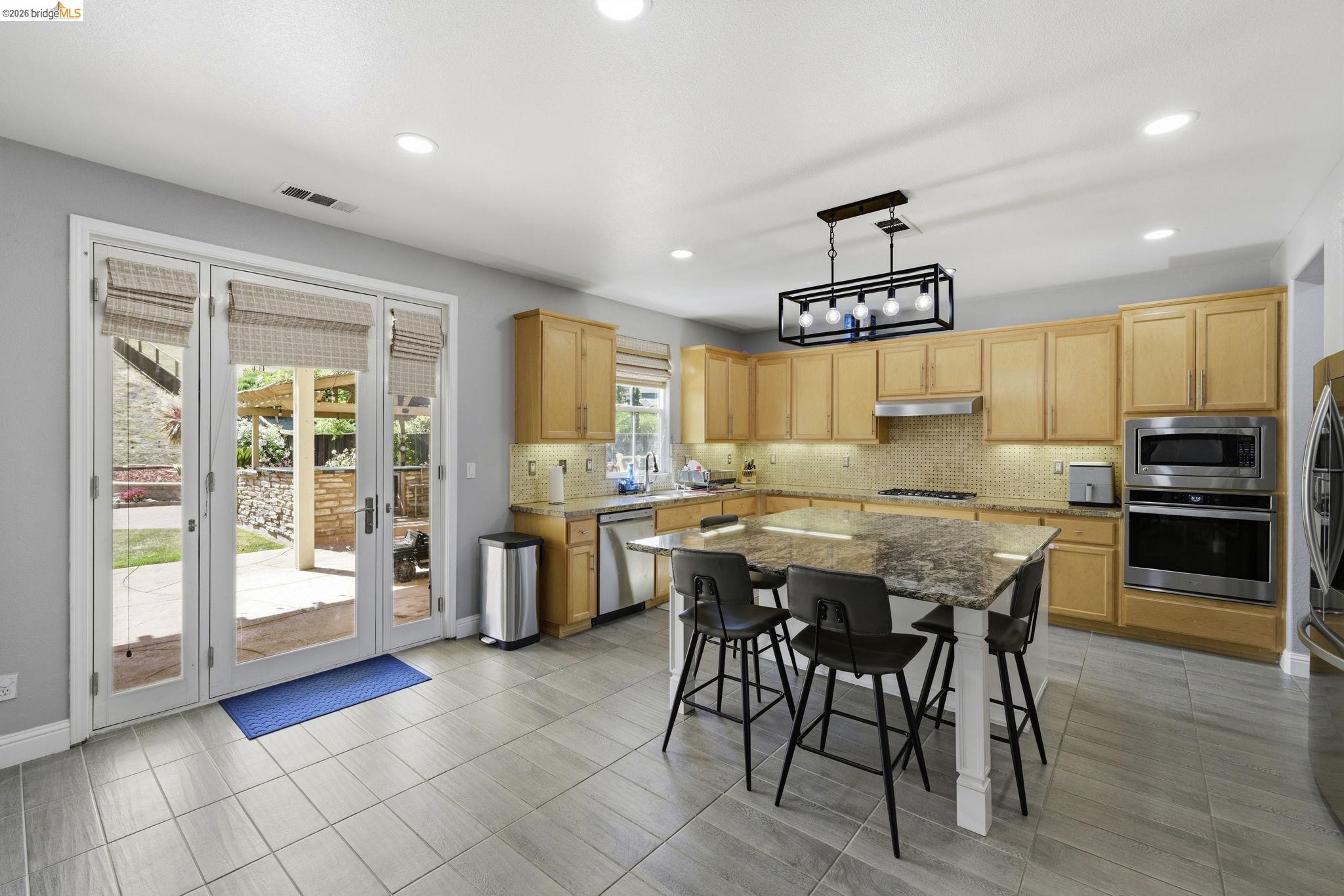 4568 Le Conte Circle Antioch, CA 94531 - Photo 26 of 36 Kitchen featuring light wood finish cabinetry, a kitchen island, stainless steel appliances, and decorative backsplash