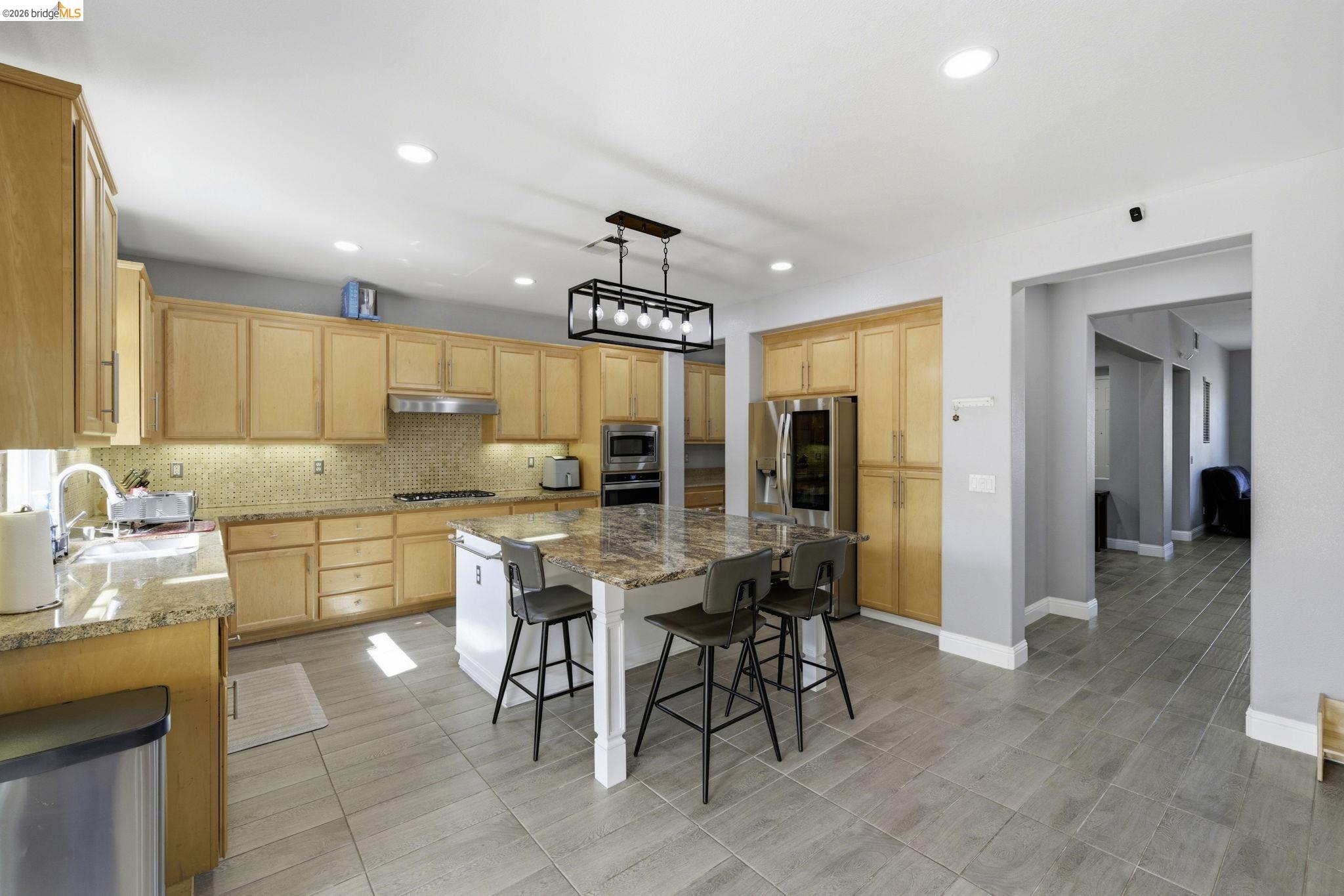 4568 Le Conte Circle Antioch, CA 94531 - Photo 27 of 36 Kitchen with light wood finish cabinets, a kitchen bar, stainless steel appliances, light stone counters, and a kitchen island
