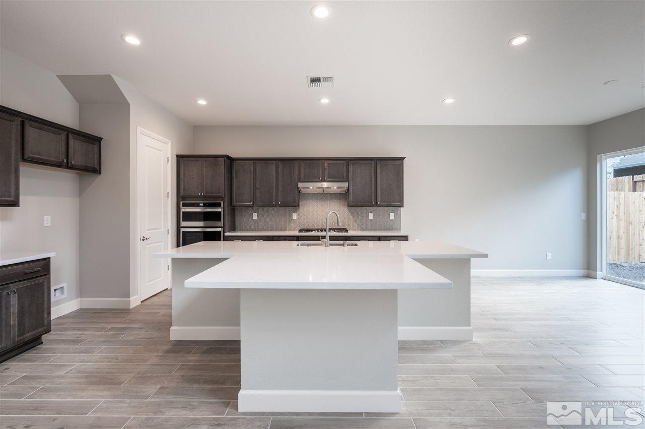 9425 Hawkshead Road, Unit HOMESITE 93 Reno, NV 89521 - Photo 4 of 11 a large kitchen with stainless steel appliances a large counter top a sink and a stove
