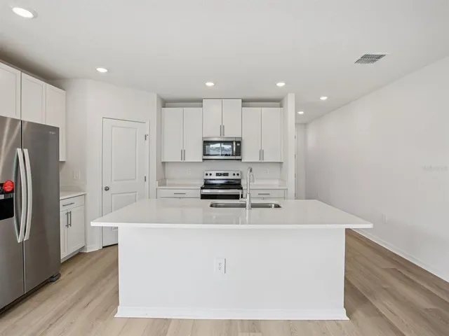 a kitchen with kitchen island a sink stainless steel appliances and refrigerator