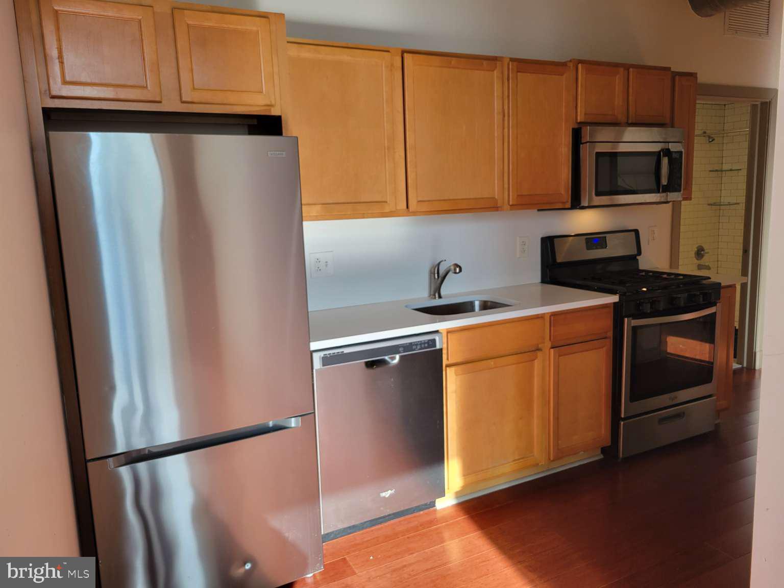 511 North Broad Street, Unit 505 Philadelphia, PA 19123 - Photo 4 of 23 a kitchen with stainless steel appliances granite countertop a refrigerator a stove a sink and dishwasher with wooden floor