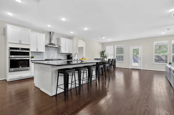 an open kitchen with wooden floor and stainless steel appliances