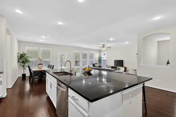 a kitchen with stainless steel appliances kitchen island granite countertop a stove a sink a refrigerator and white cabinets with wooden floor