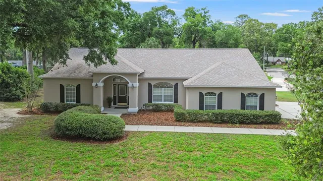 an aerial view of a house with swimming pool and large trees