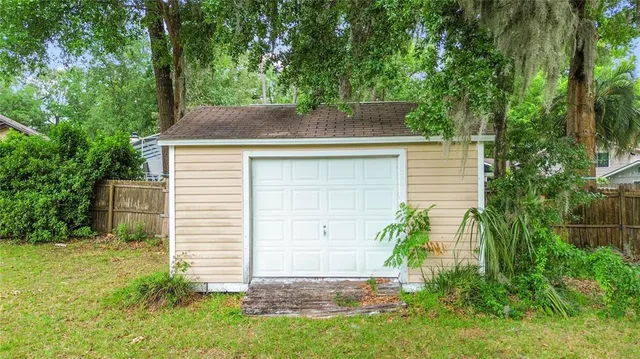 a backyard of a house with plants and large tree