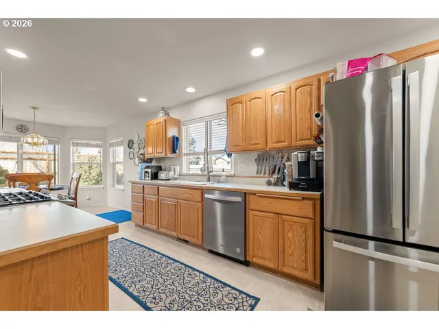 a kitchen with stainless steel appliances granite countertop a refrigerator a stove a sink dishwasher and a microwave with wooden floor