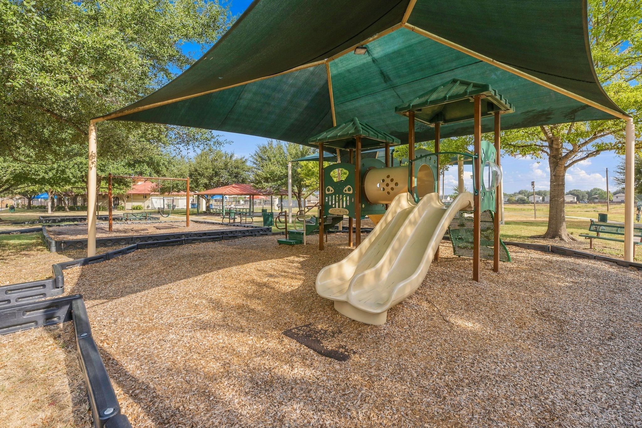 9004 Wiley Way Austin, TX 78747 - Photo 32 of 39 Shaded neighborhood play structures and swings rest beneath mature shade trees.