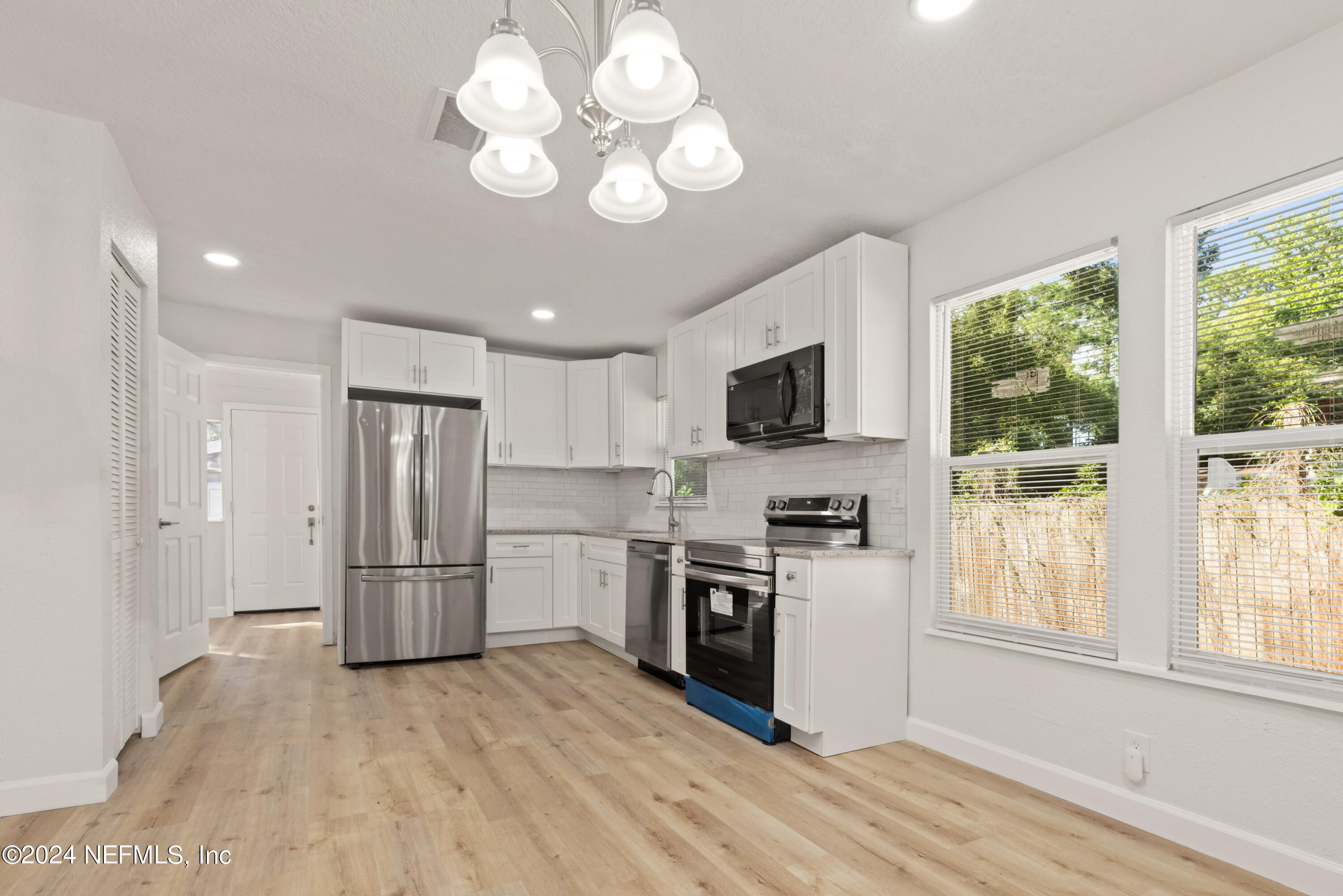 2448 Parental Home Road Jacksonville, FL 32216 - Photo 6 of 21 a kitchen with stainless steel appliances granite countertop a refrigerator a stove a sink dishwasher a oven with white cabinets and wooden floor