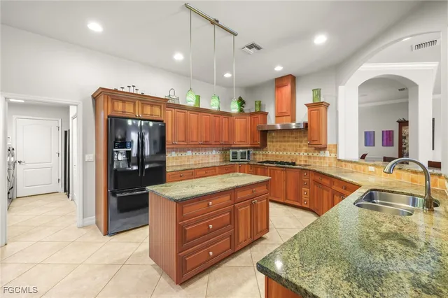 a large kitchen with kitchen island a large counter top stainless steel appliances and cabinets
