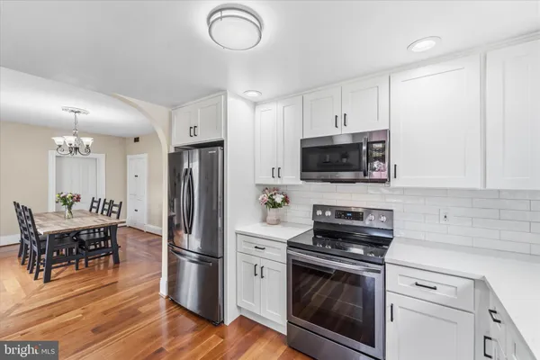 a kitchen with stainless steel appliances a stove a refrigerator and a white cabinets