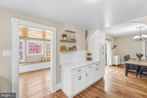 a hallway with white cabinets and wooden floor