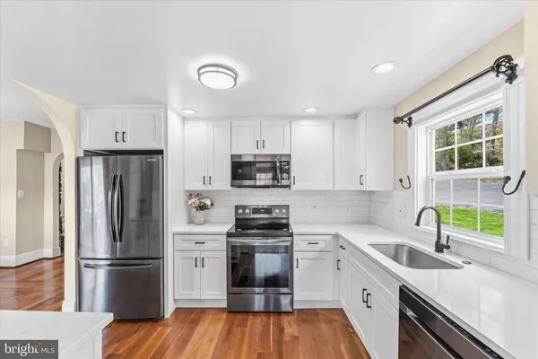 a kitchen with granite countertop stainless steel appliances a sink a refrigerator a window and cabinets
