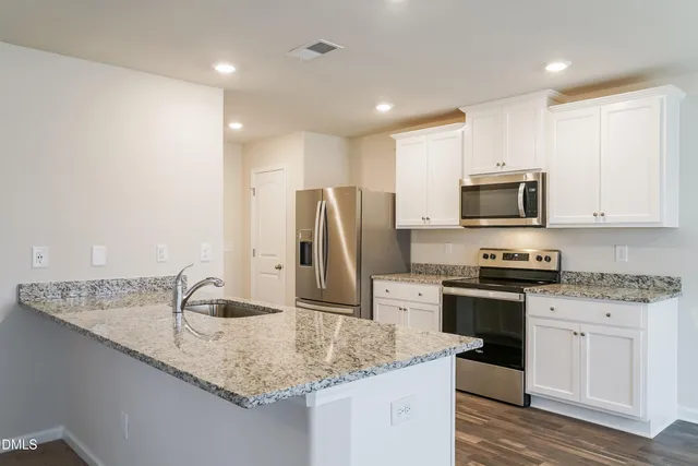 a kitchen with stainless steel appliances granite countertop a sink a stove and a refrigerator