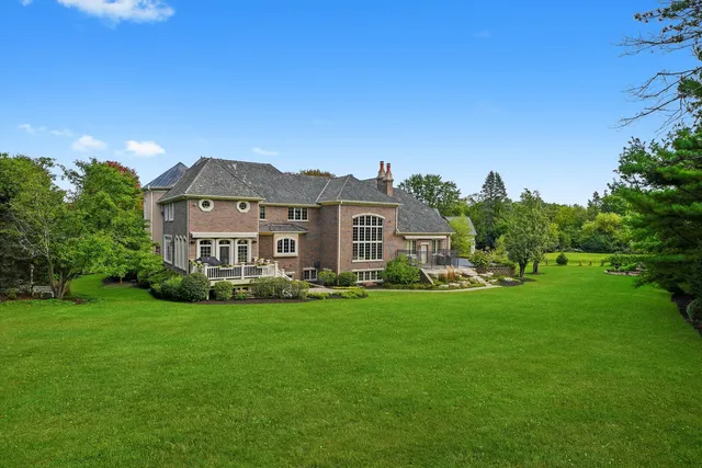 a view of a house with a big yard potted plants and large tree