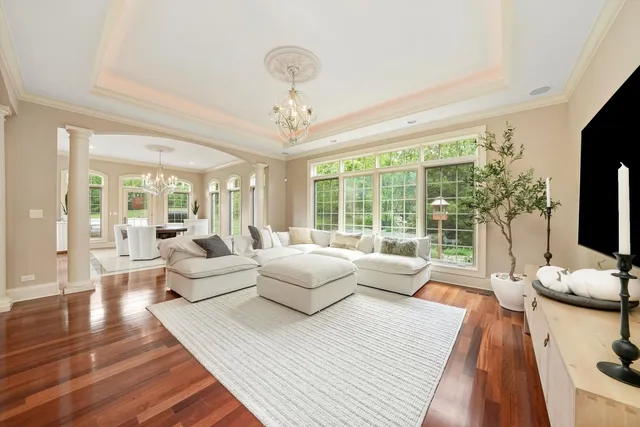 a living room with furniture large windows and wooden floor