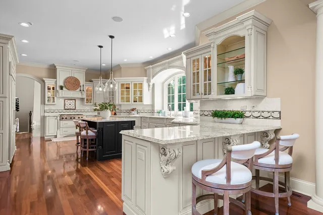 a kitchen with stainless steel appliances granite countertop a stove a sink dishwasher a dining table and chairs with wooden floor