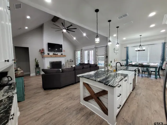 a kitchen with granite countertop a refrigerator and white cabinets