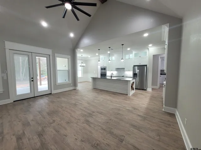 a large white kitchen with a large counter top space a sink stainless steel appliances and cabinets