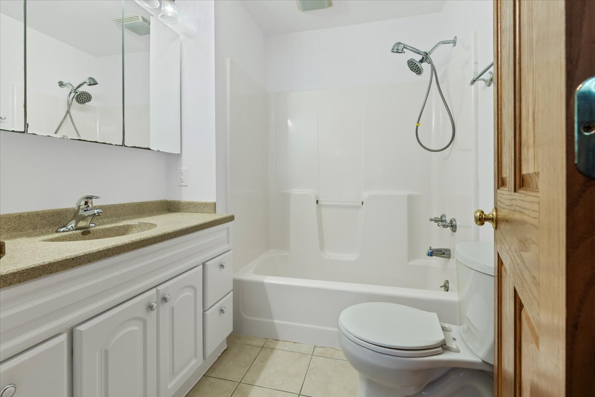 717 Edward Street Sycamore, IL 60178 - Photo 12 of 21 a bathroom with a granite countertop sink a toilet and a bathtub