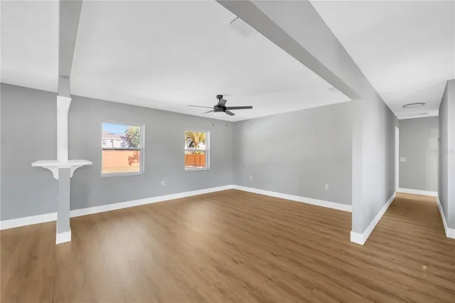 an empty room with wooden floor and windows