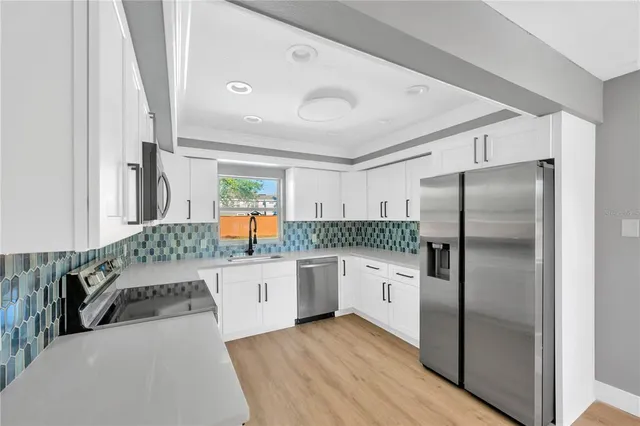a kitchen with stainless steel appliances granite countertop a sink cabinets and wooden floor