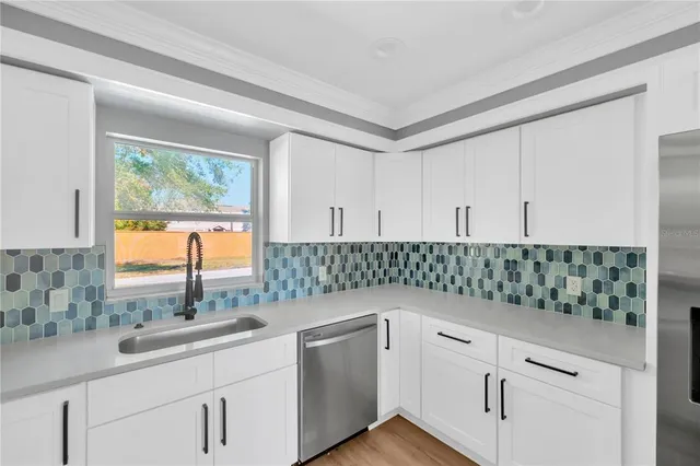 a kitchen with white cabinets and window