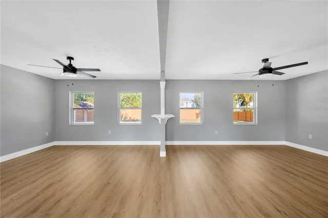 a view of an empty room with window and wooden floor