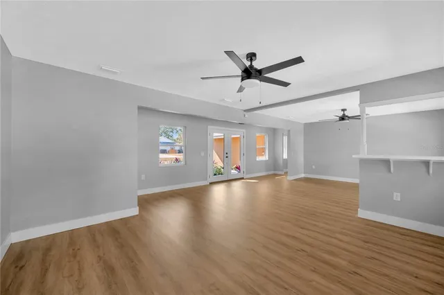 a view of empty room with wooden floor and ceiling fan