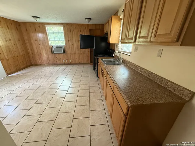 a kitchen with granite countertop a sink cabinets and appliances
