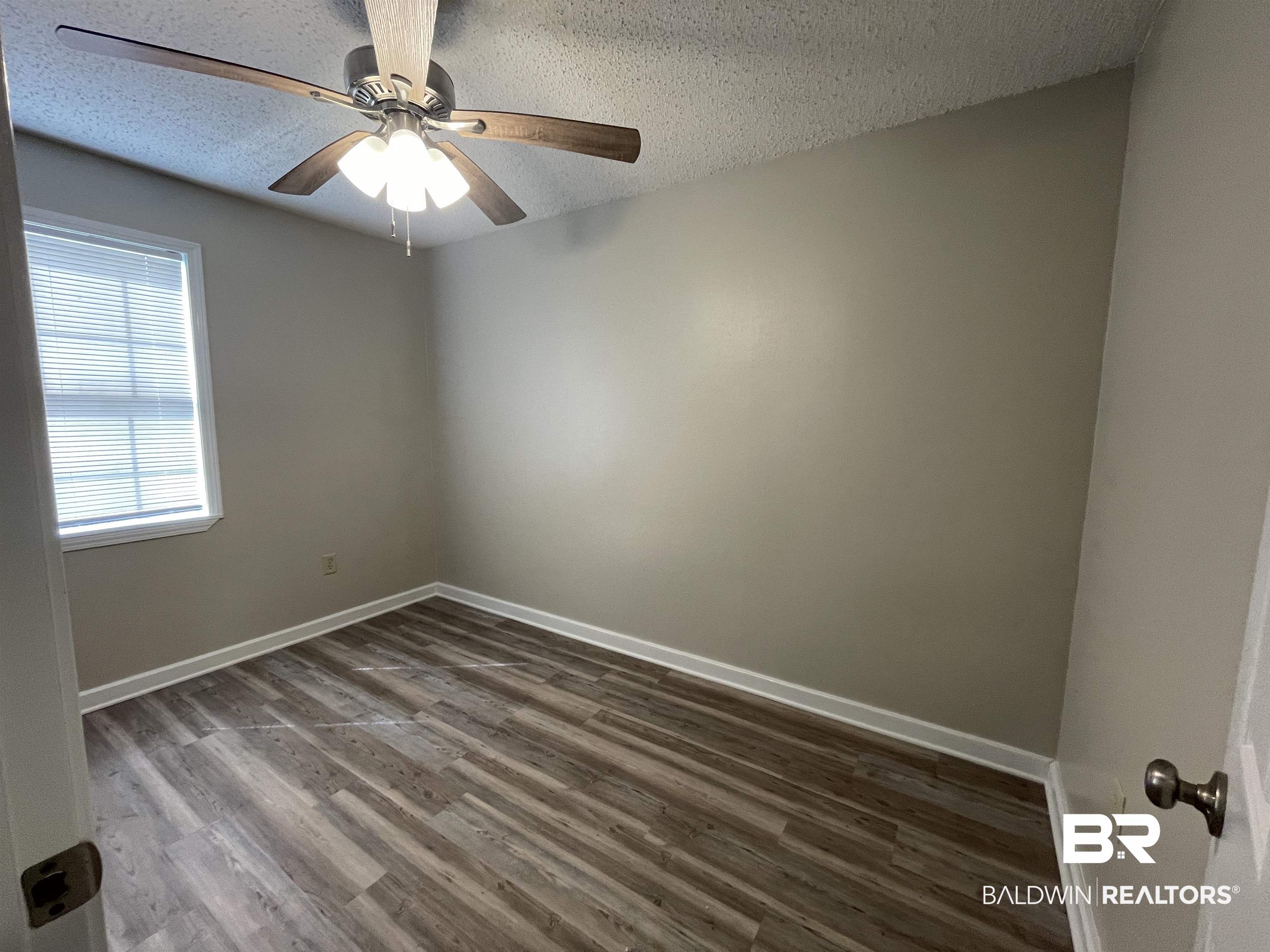 28414 Highway 31 Flomaton, AL 36441 - Photo 10 of 11 Unfurnished room featuring ceiling fan, a textured ceiling, baseboards, and wood finished floors