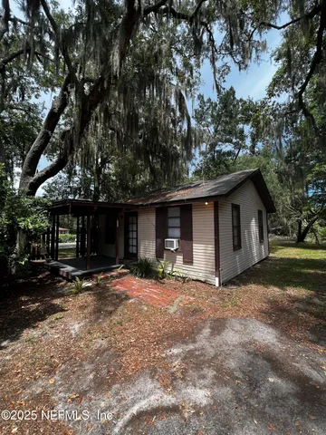 a view of a house with a large tree and a yard
